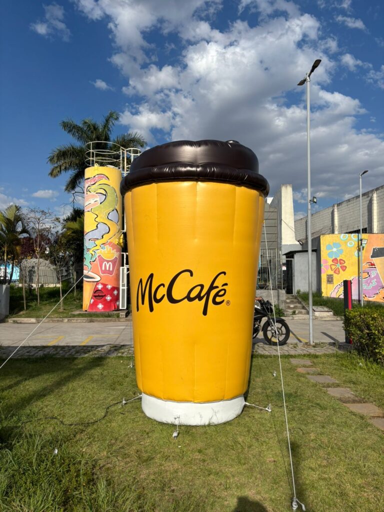 Réplica inflável do copo do McCafé atracada no gramado da entrada de uma loja do McDonald's